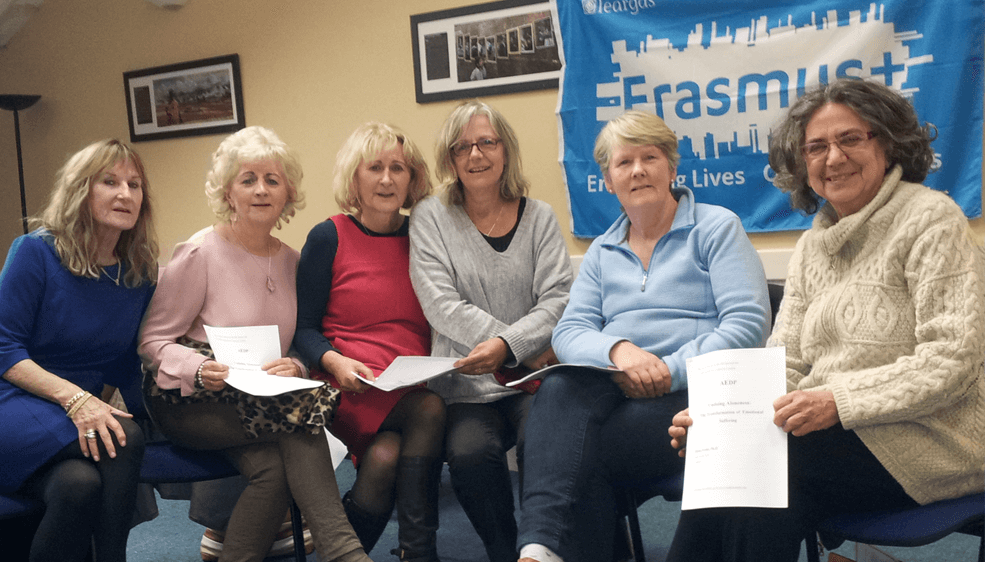 SHEP Adult Education staff sitting in front of an Erasmus+ flag