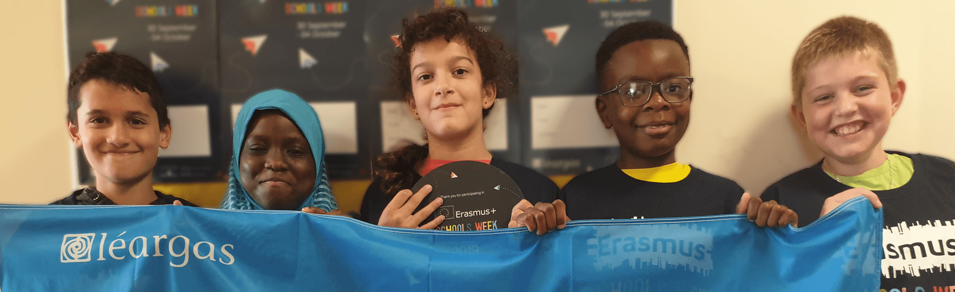 A group of 5 students smiling and holding a blue flag