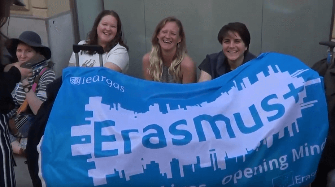 A group of VET learners participating in a project holding a blue flag that reads Erasmus+
