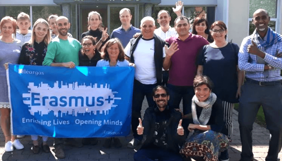 A large group of participants holding an Erasmus+ flag