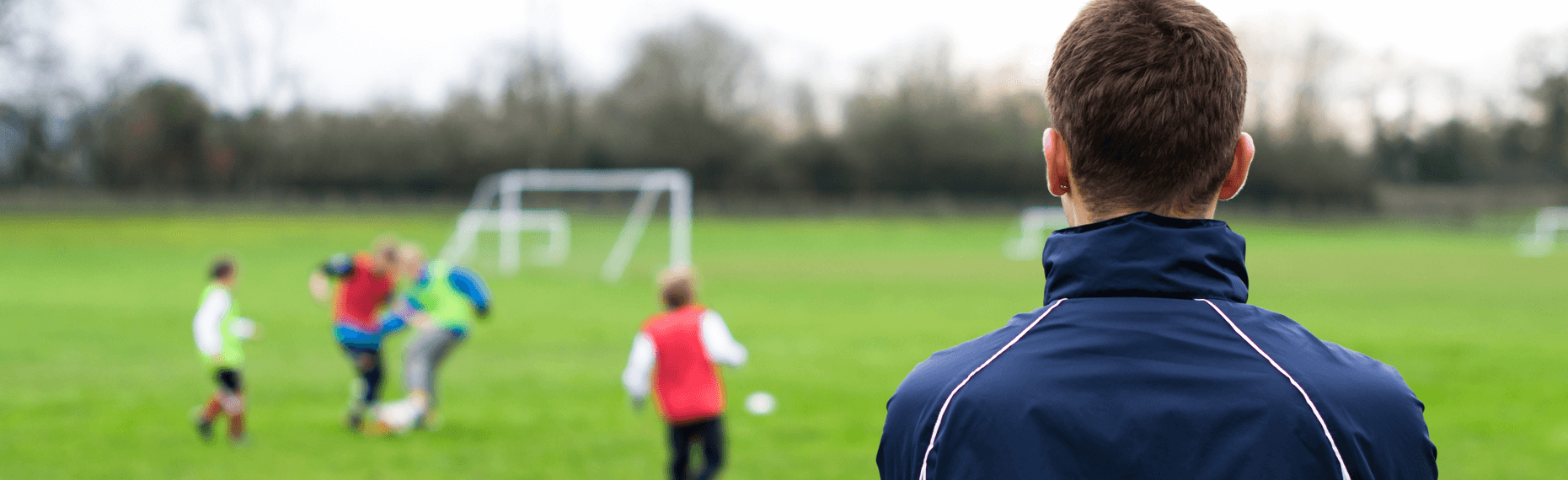 Grass-roots coach trains young people on a football pitch